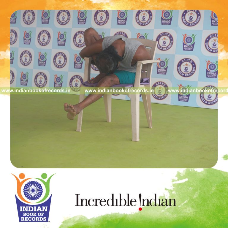 individual holding daksina marichyasana yoga pose blindfolded on a chair for record in Indian Book of Records