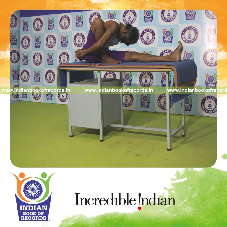 individual holding daksina marichyasana yoga pose blindfolded on a table for record in Indian Book of Records