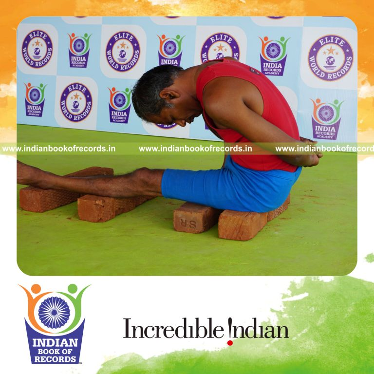 individual holding daksina marichyasana yoga pose on bricks for record in Indian Book of Records