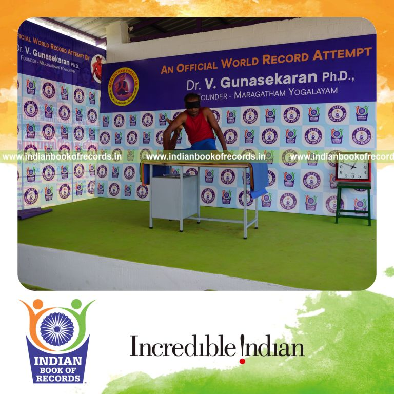 individual holding daksina mrigasana yoga pose blindfolded on a table for record in Indian Book of Records
