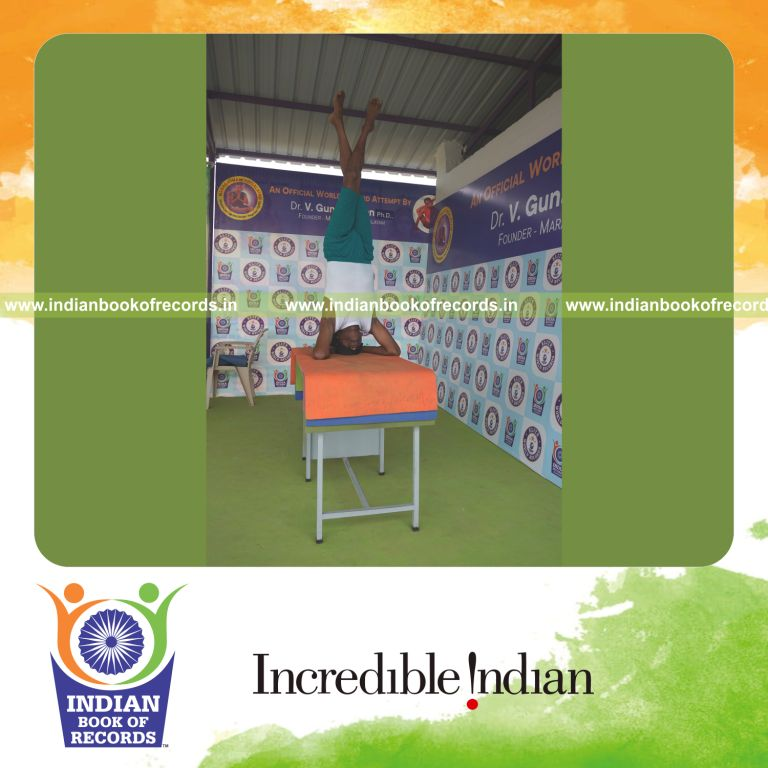 an individual holding daksina parivrtaikapata salamba sirsasana yoga pose blindfolded on a table continuously for the longest duration with control and balance for a record in Indian Book of Records