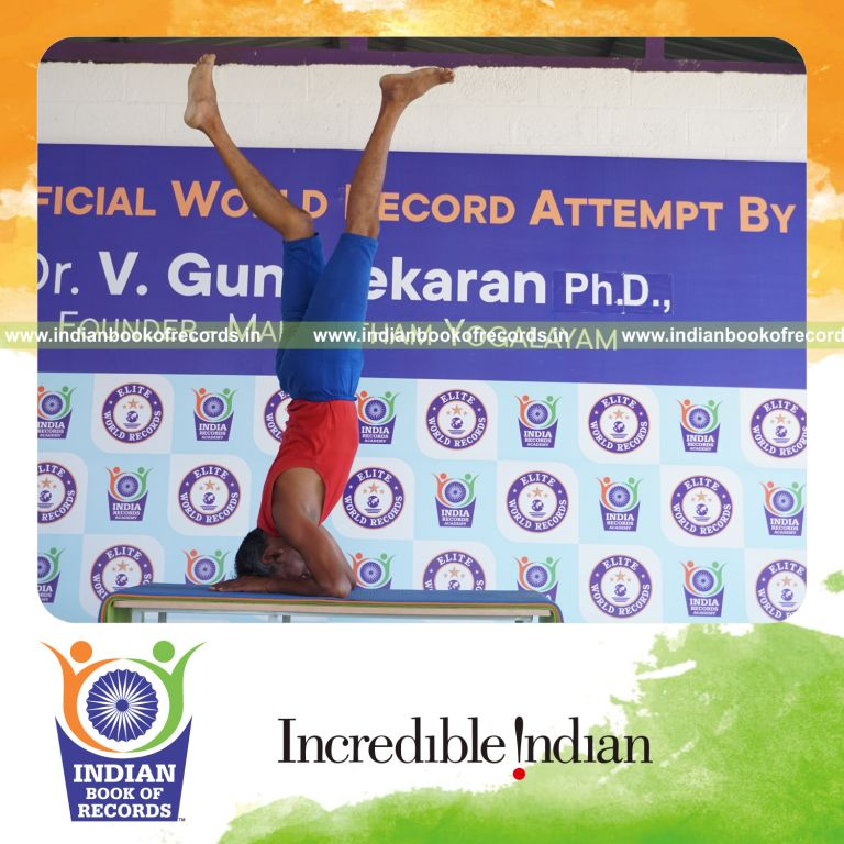 individual holding daksina parivrtaikapata salamba sirsasana yoga pose on a table for record in Indian Book of Records