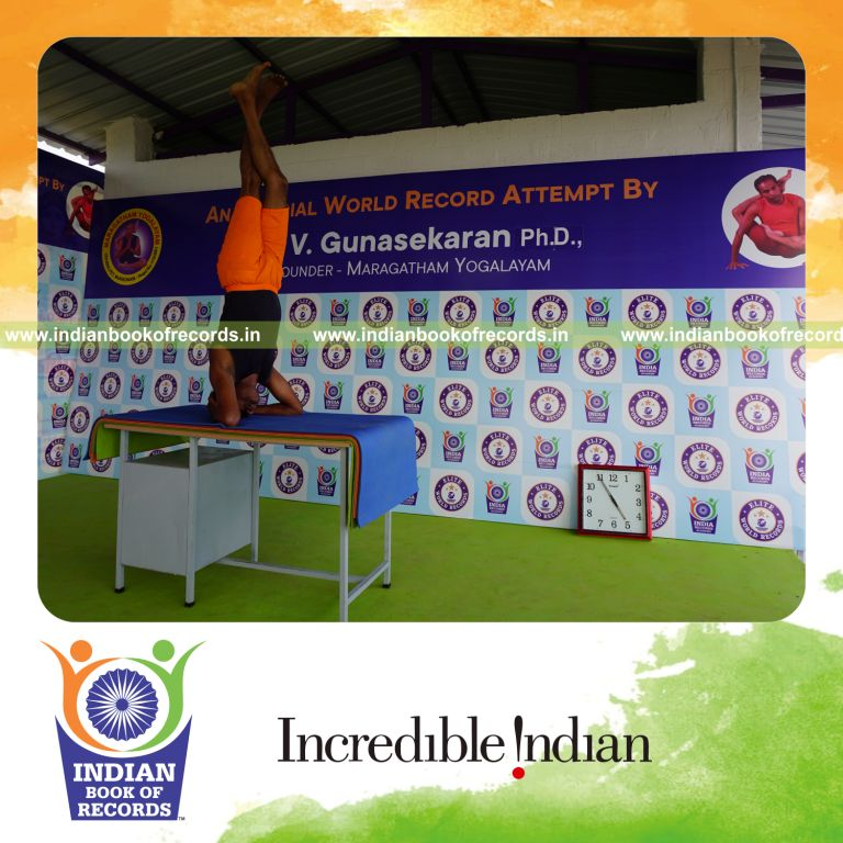 individual holding daksina parivrtaikapata sirsasana yoga pose blindfolded on a table for record in Indian Book of Records