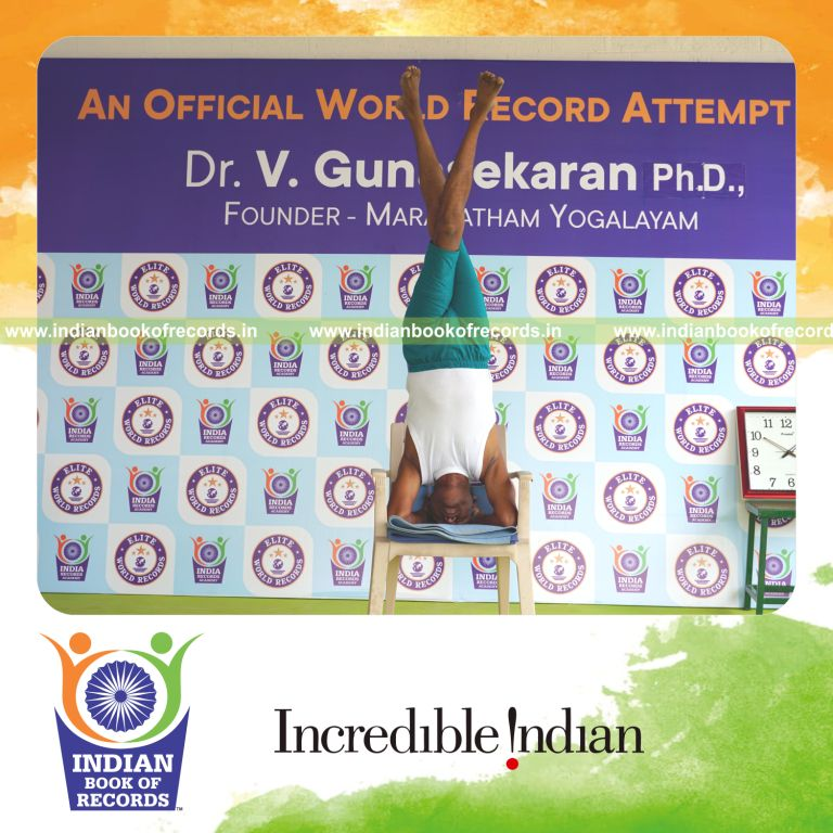 individual holding daksina parivrtaikapata sirsasana yoga pose on a chair for record in Indian Book of Records