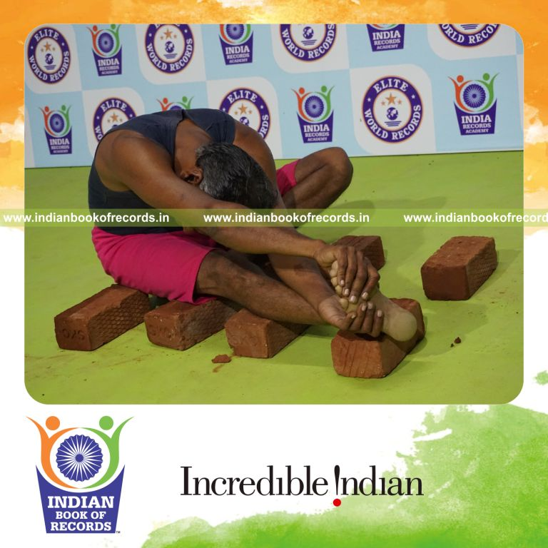 individual holding daksina parivrtana janu sirsasana yoga pose on bricks for record in Indian Book of Records