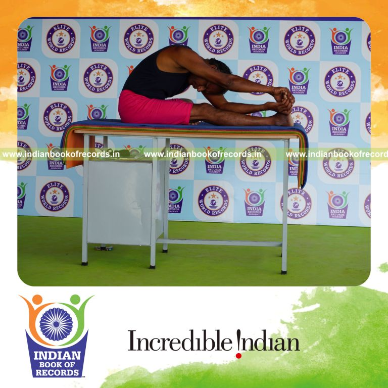 individual holding daksina parivrtana janu sirsasana yoga pose on a table for record in Indian Book of Records