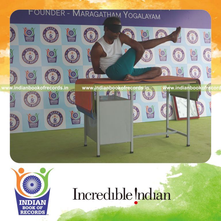 an individual holding daksina parivrtta ardha matsyendrasana yoga pose blindfolded on a table continuously for the longest duration with stability and control for a record in Indian Book of Records