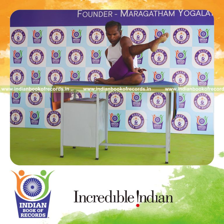 individual holding daksina parivrtta ardha matsyendrasana yoga pose on a table for record in Indian Book of Records