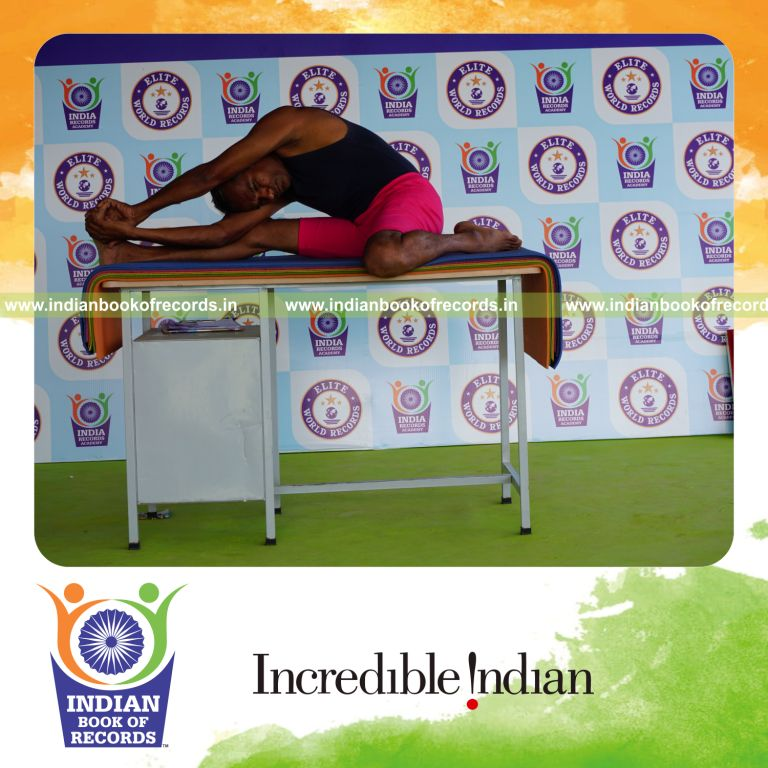 individual holding daksina parivrtta gomukha janu sirsasana yoga pose on a table for record in Indian Book of Records