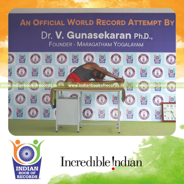 individual holding daksina parivrtta janu sirsasana yoga pose blindfolded on a table for record in Indian Book of Records