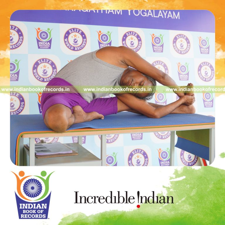 individual holding daksina parivrtta janu sirsasana yoga pose on a table for record in Indian Book of Records