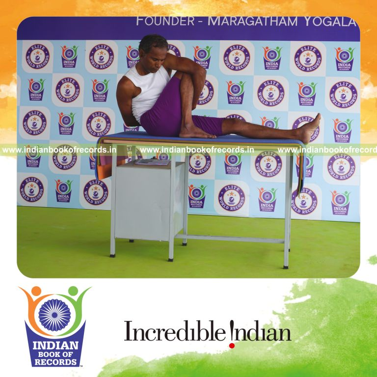 individual holding daksina parivrtta marichyasana yoga pose on a table for record in Indian Book of Records