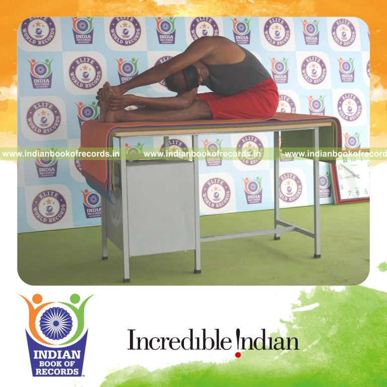 individual holding daksina parivrtta paschimottanasana yoga pose blindfolded on a table for record in Indian Book of Records