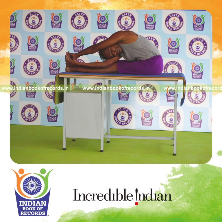 individual holding daksina parivrtta paschimottanasana yoga pose on a table for record in Indian Book of Records