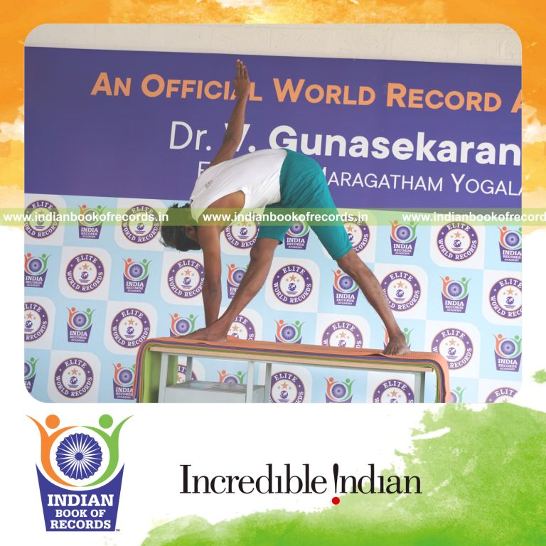 an individual holding daksina parivrtta trikonasana yoga pose blindfolded on a table continuously for the longest duration with control and balance for a record in Indian Book of Records