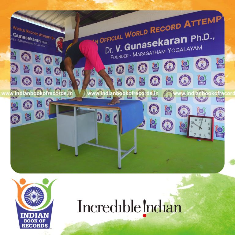 an individual holding daksina parivrtta trikonasana yoga pose on a table for the longest duration with flexibility and balance for a record in Indian Book of Records