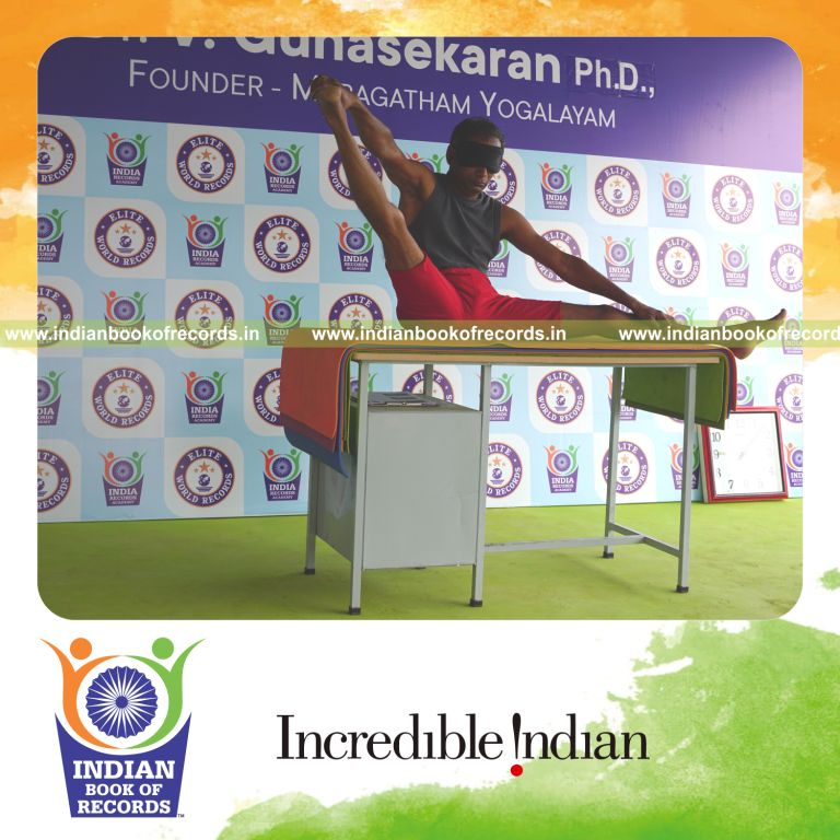 individual holding daksina parsva akarna dhanurasana yoga pose blindfolded on a table for record in Indian Book of Records