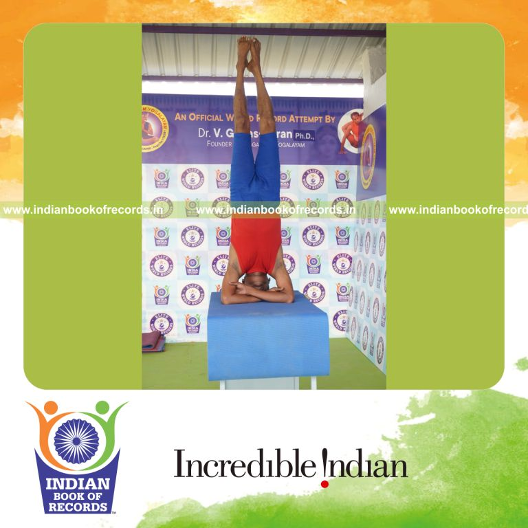 individual holding daksina parsva baddha hastha sirsasana yoga pose on a table for record in Indian Book of Records