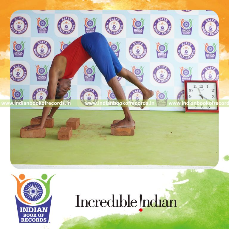 individual holding daksina parsva ekapada adho mukha svanasana yoga pose on bricks for record in Indian Book of Records