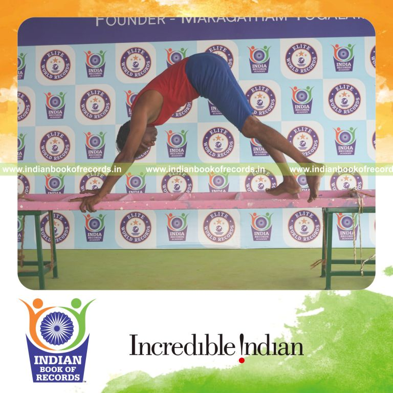 individual holding daksina parsva ekapada adho mukha svanasana yoga pose on a ladder for record in Indian Book of Records