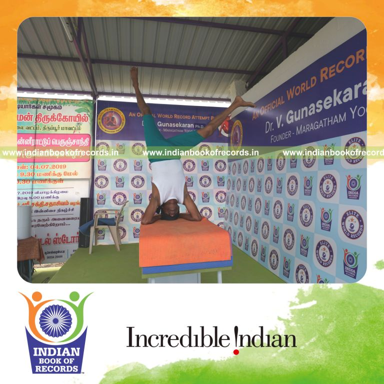 an individual holding daksina parsva ekapada salamba sirsasana yoga pose blindfolded on a table continuously for the longest duration with control and balance for a record in Indian Book of Records