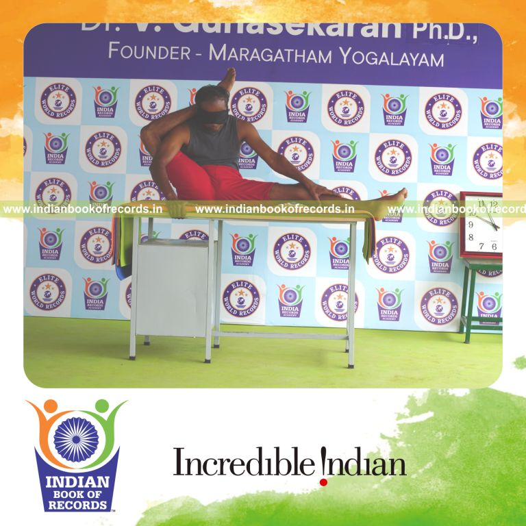individual holding daksina parsva ekapada sirsasana yoga pose blindfolded on a table for record in Indian Book of Records