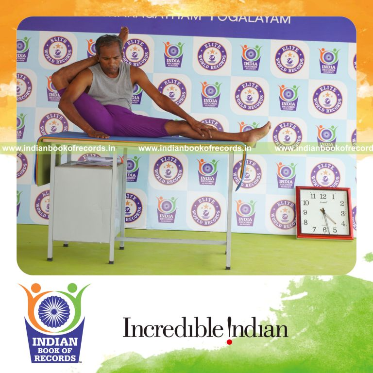 individual holding daksina parsva ekapada sirsasana yoga pose on a table for record in Indian Book of Records