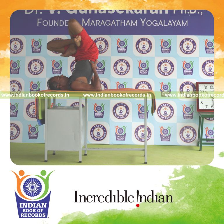 individual holding daksina parsva padma sarvangasana yoga pose on a table for record in Indian Book of Records