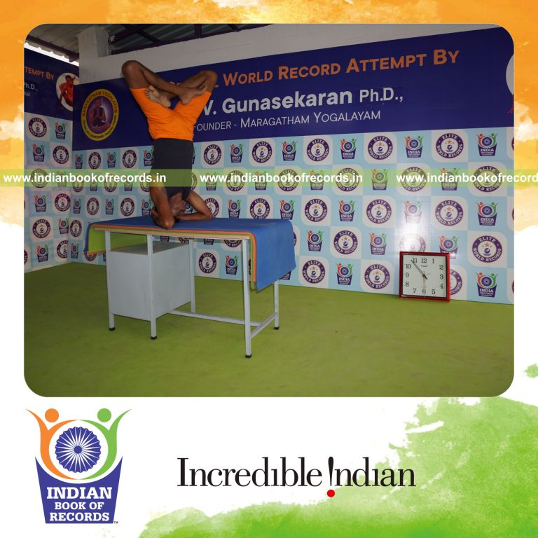 individual holding daksina parsva padma sirsasana yoga pose blindfolded on a table for record in Indian Book of Records