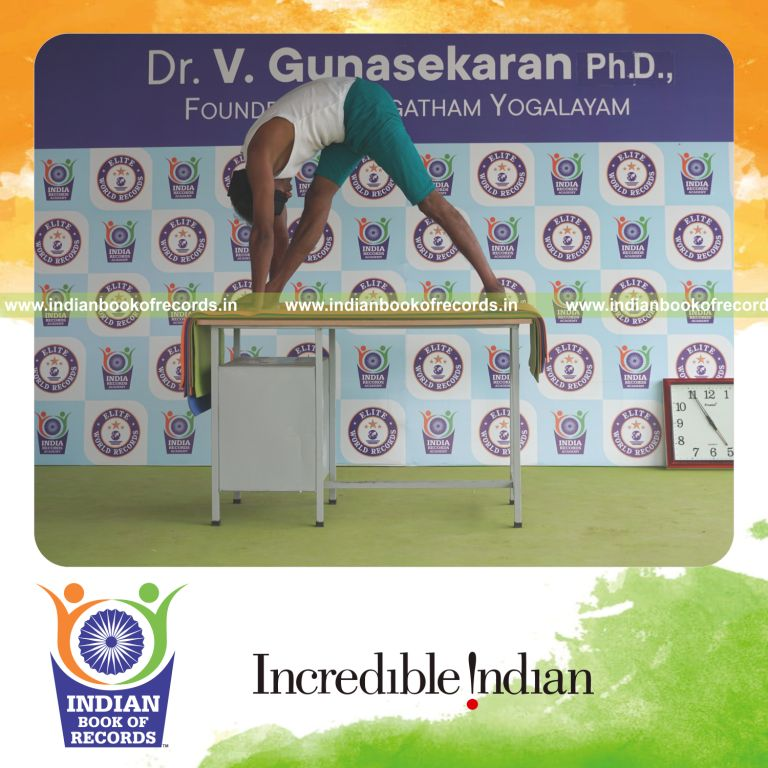 an individual holding daksina parsvottanasana yoga pose blindfolded on a table continuously for the longest duration with balance and control for a record in Indian Book of Records