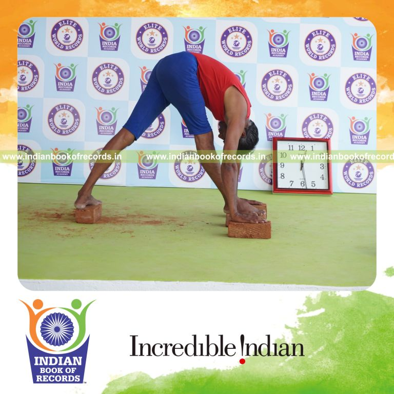 individual holding daksina parsvottanasana yoga pose on bricks for record in Indian Book of Records