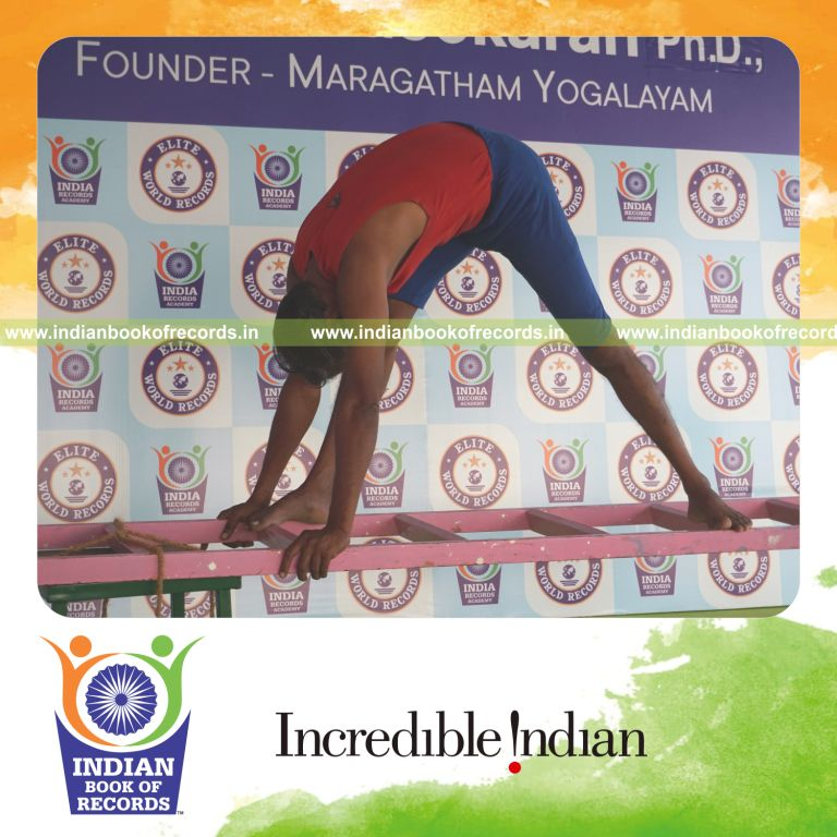 individual holding daksina parsvottanasana yoga pose on a ladder for record in Indian Book of Records