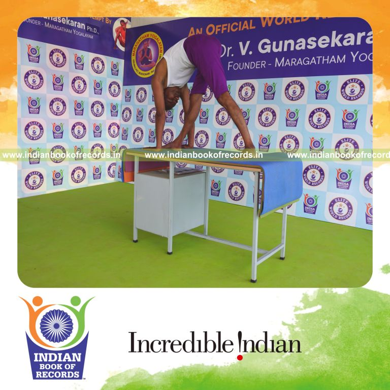 individual holding daksina parsvottanasana yoga pose on a table for record in Indian Book of Records