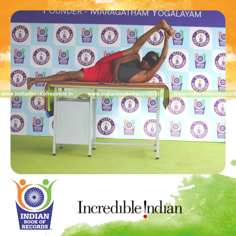individual holding daksina purna anandasana yoga pose blindfolded on a table for record in Indian Book of Records