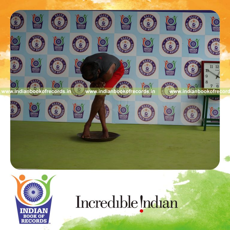 individual holding daksina purna garudasana yoga pose blindfolded on a brass plate for record in Indian Book of Records