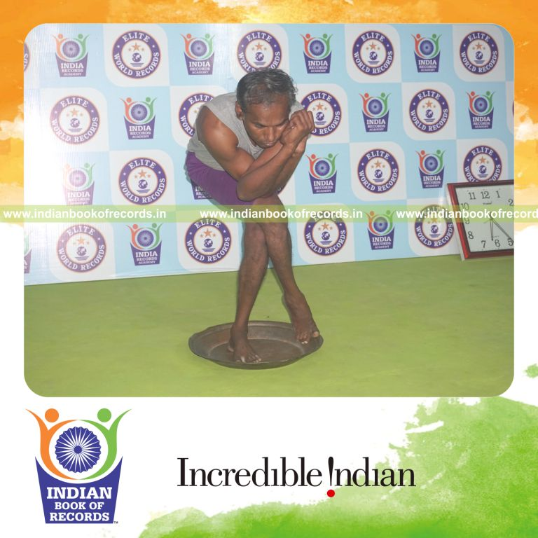 individual holding daksina purna garudasana yoga pose on a brass plate for record in Indian Book of Records