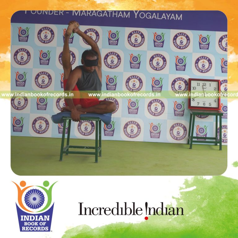 individual holding daksina purna krounchasana yoga pose blindfolded on a stool for record in Indian Book of Records