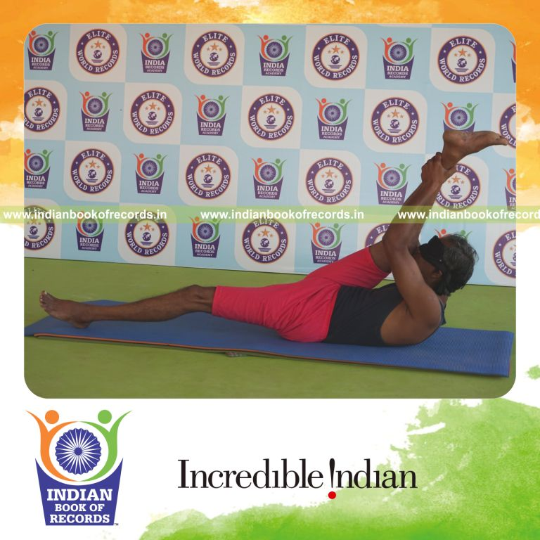 individual holding daksina supta padangusthasana yoga pose blindfolded for record in Indian Book of Records