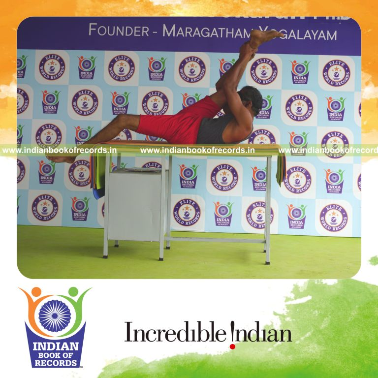 individual holding daksina supta padangusthasana yoga pose blindfolded on a table for record in Indian Book of Records
