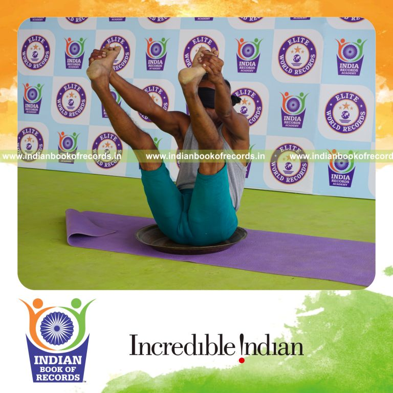 individual holding enkonasana yoga pose blindfolded on a brass plate for record in Indian Book of Records