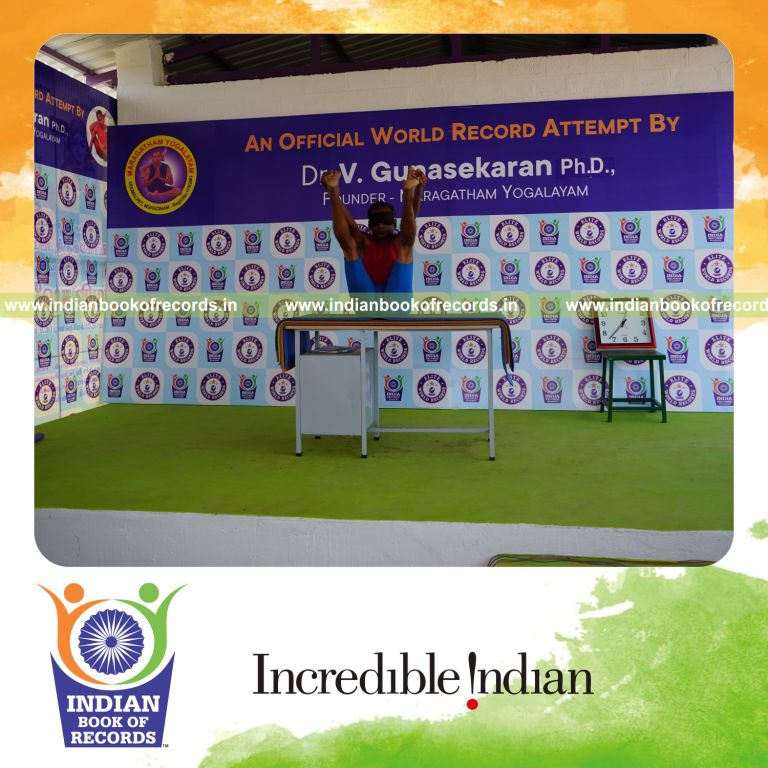 individual holding enkonasana yoga pose blindfolded on a table for record in Indian Book of Records