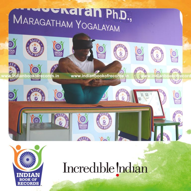 an individual holding garbha pindasana yoga pose blindfolded on a table continuously for the longest duration with stability and control for a record in Indian Book of Records
