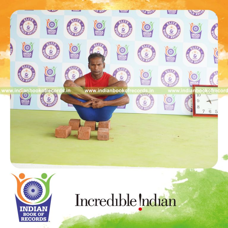 individual holding garbha pindasana yoga pose on bricks for record in Indian Book of Records