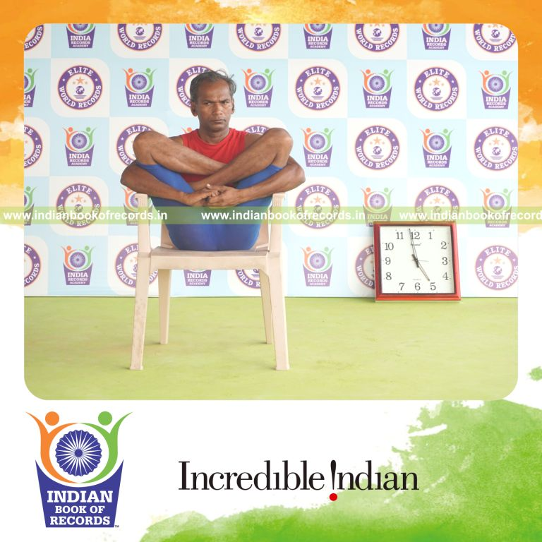 individual holding garbha pindasana yoga pose on a chair for record in Indian Book of Records