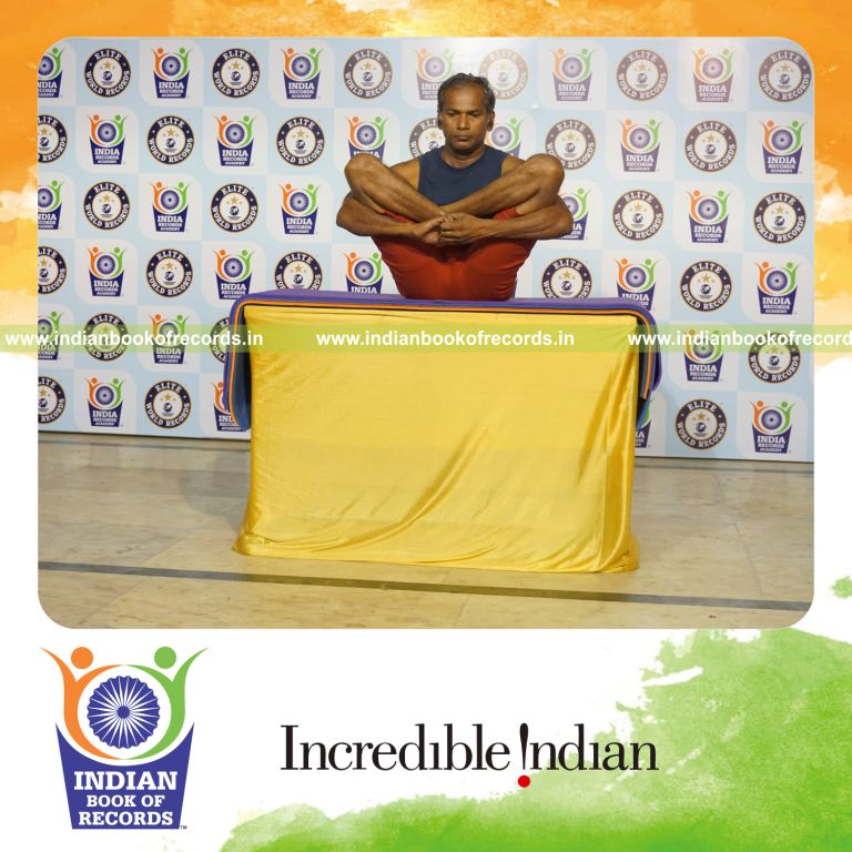 individual holding garbha pindasana yoga pose on a table for record in Indian Book of Records