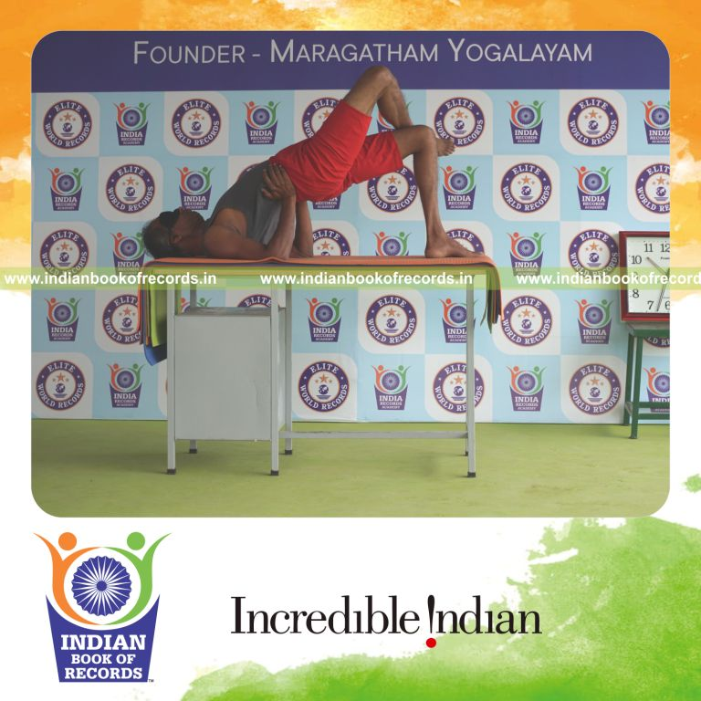 individual holding garuda setu bandha sarvangasana yoga pose blindfolded on a table for record in Indian Book of Records