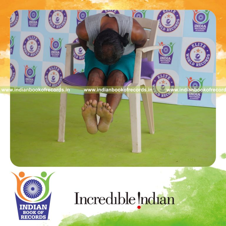 individual holding gopura paschimottanasana yoga pose blindfolded on a chair for record in Indian Book of Records