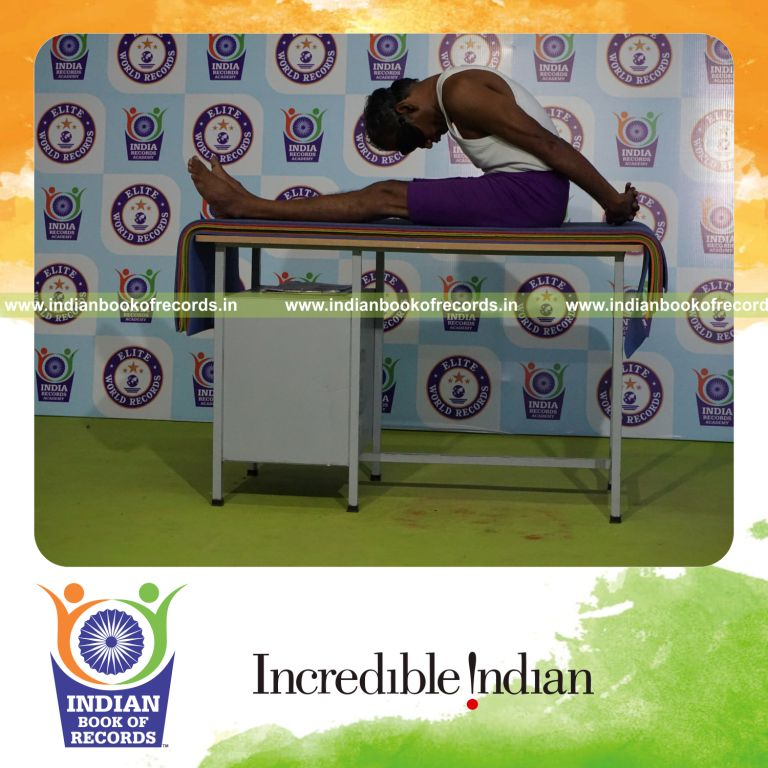 individual holding gopura paschimottanasana yoga pose blindfolded on a table for record in Indian Book of Records
