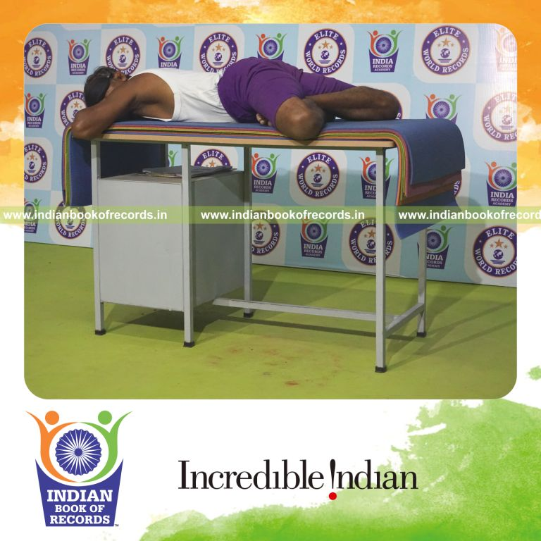 individual holding guptasana yoga pose blindfolded on a table for record in Indian Book of Records