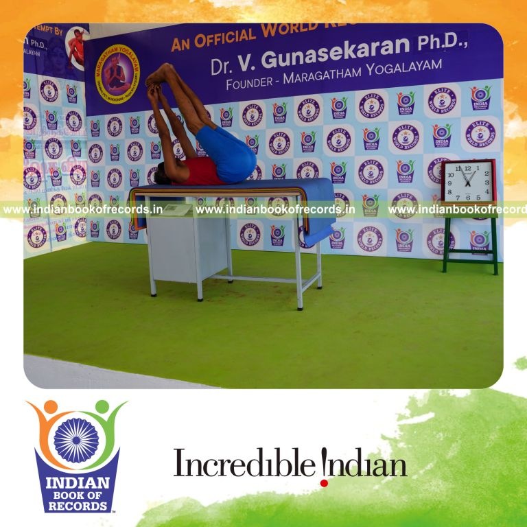 individual holding julasana yoga pose blindfolded on a table for record in Indian Book of Records